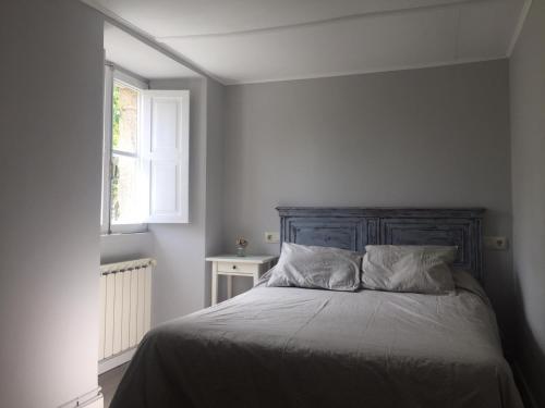 a bedroom with a bed with a wooden headboard and a window at Casa Labazá in Villarmayor