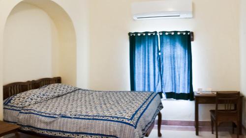 a bedroom with a bed and a blue curtain at Neemrana's - Tijara Fort Palace in Alwar