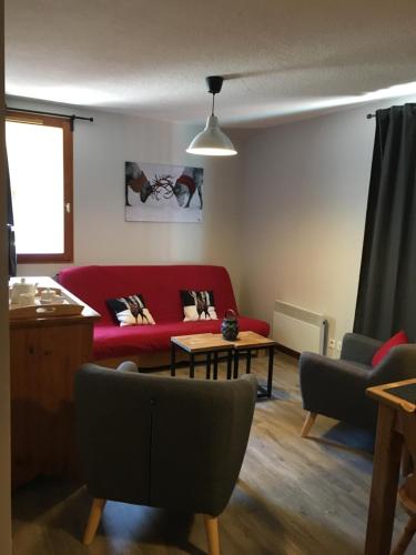 un salon avec un canapé rouge et une table dans l'établissement Les Balcons de Vaujany, à Vaujany