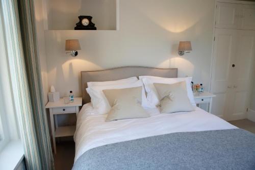 a bed with white pillows and a clock on the wall at Saddlers B&B in Funtington