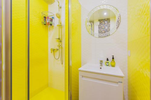 a yellow bathroom with a sink and a shower at Sunny apartments on Yulii Zdanovskoi st 36b in Kyiv