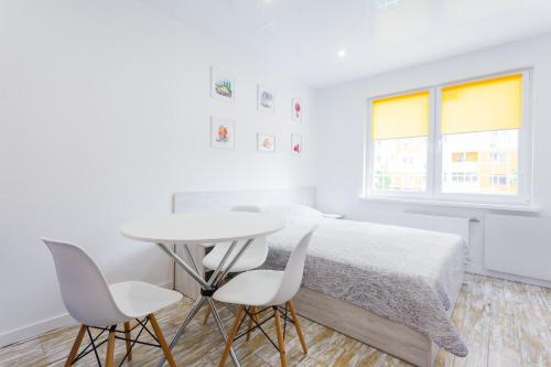 a white bedroom with a bed and a table and chairs at Sunny apartments on Yulii Zdanovskoi st 36b in Kyiv