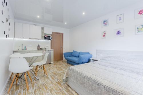 a bedroom with a bed and a desk and a kitchen at Sunny apartments on Yulii Zdanovskoi st 36b in Kyiv