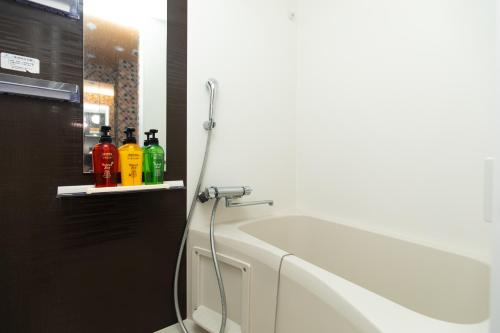a white bath tub with a hose on a shelf at Guest House One More Heart at TSUKIJI 1 in Tokyo