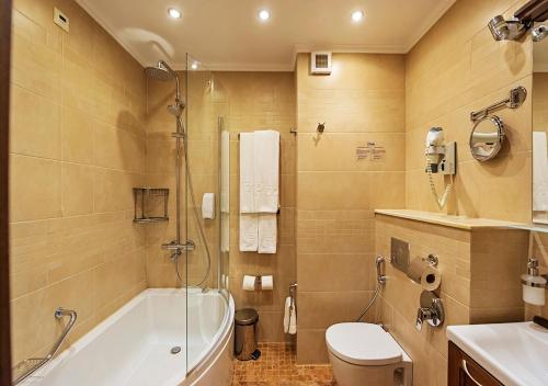 a bathroom with a tub and a toilet and a sink at 7 Pools SPA Boutique Hotel in Bansko