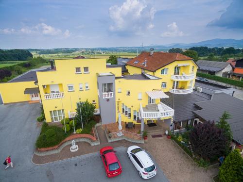 a yellow house with cars parked in a parking lot at Hotel Orion in Ivanec