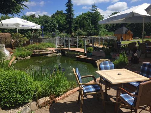 a table and chairs next to a pond with a bridge at Hotel Wikingerhof in Kropp