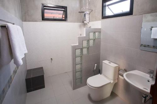 a white bathroom with a toilet and a sink at พืชไทยเชียงคาน(Plantthai) in Chiang Khan