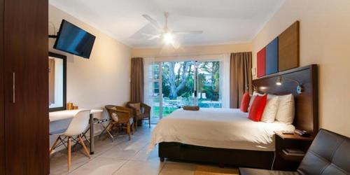 a hotel room with a bed and a table and chairs at Africa Beach B&B in Port Elizabeth