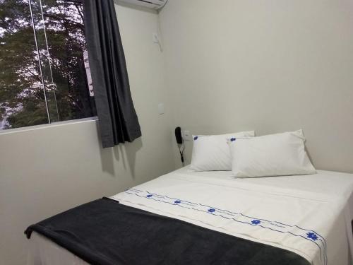 a bedroom with a bed with a window and a phone at Hotel Flor Paulista in São Paulo