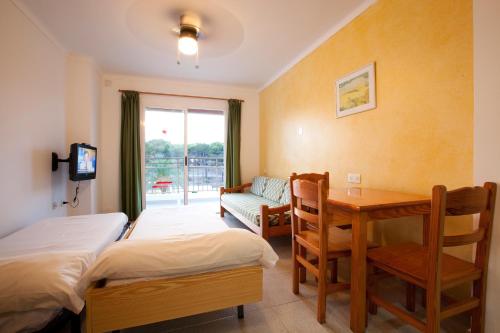 1 dormitorio con cama, escritorio y mesa en Apartamentos Playa Es Cana, en Es Canar