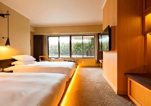 高松市にあるロイヤルパークホテル高松のベッド2台とテレビが備わるホテルルームです。