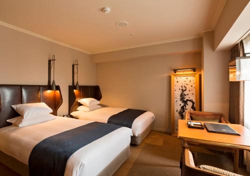 a hotel room with two beds and a desk at Royal Park Hotel Takamatsu in Takamatsu