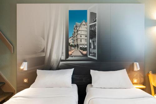 two beds in a room with two pictures on the wall at B&B HOTEL Angers 1 Beaucouzé in Beaucouzé