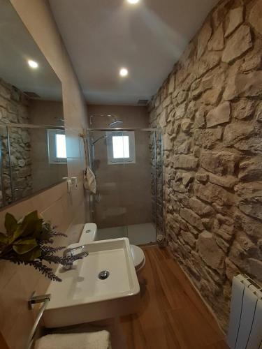 a bathroom with a sink and a stone wall at Casa La Foradada in Corbera