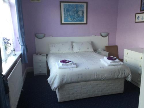 a bedroom with a white bed with purple walls at Merlewood in Skegness