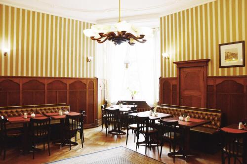 une salle à manger avec des tables et des chaises ainsi qu'un lustre dans l'établissement Hotel Pension Bella, à Berlin