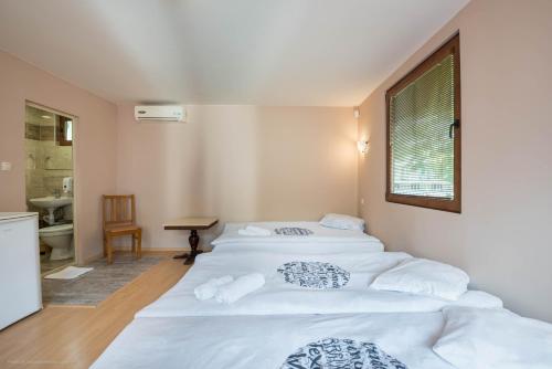 a bedroom with two white beds and a bathroom at Стаи за гости АЯКС Guest rooms AJAX in Kranevo