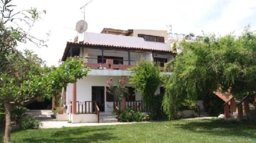 a large house with a yard with trees in front of it at Maria's Apartments in Kalyves