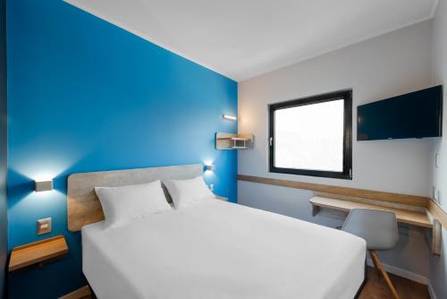 
a bedroom with a white bed and a blue wall at ibis budget Santiago Providencia in Santiago
