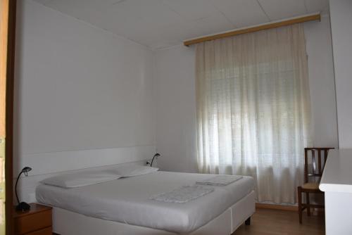 Cama blanca en habitación con ventana en Villa Dina en Riva del Garda