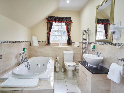 ein Badezimmer mit einer Badewanne, einem WC und einem Waschbecken in der Unterkunft Hempstead House Hotel & Restaurant in Sittingbourne