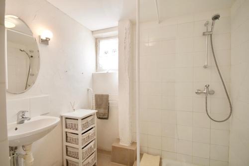 une salle de bain blanche avec un lavabo et une douche dans l'établissement Le Cuvier, à Sarlat-la-Canéda