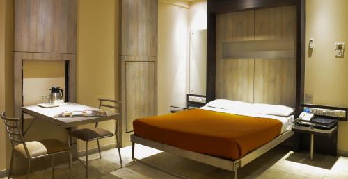 een slaapkamer met een bed, een tafel en een bureau bij Rama Krishna Hotel in Mumbai