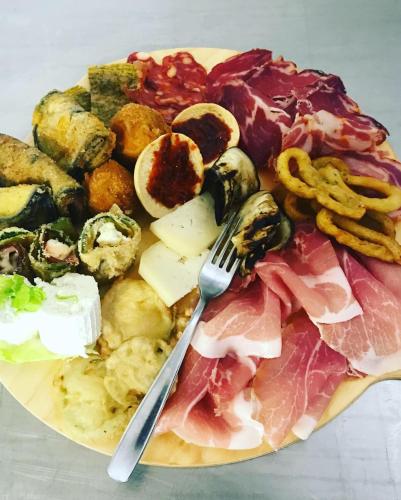 a plate of food with a fork and meats and cheese at B&B Ristorante Grotta Del Romito in Papasidero