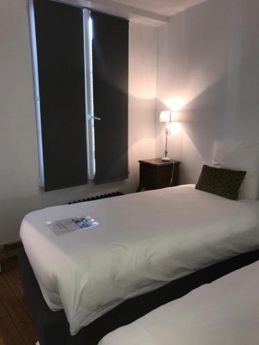 a bedroom with a large white bed with a window at La Menuiserie in Épernay