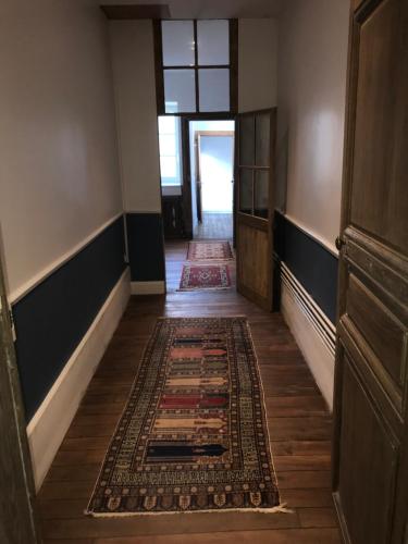 a hallway with a rug on the floor and a door at La Menuiserie in Épernay