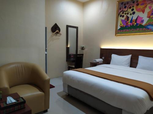 a hotel room with a bed and a chair at Hotel Grand Royal in Paklintingan