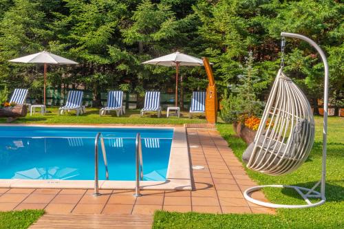 a hammock next to a swimming pool with chairs and umbrellas at Sport Hotel Village in Soldeu