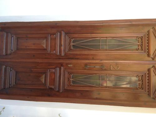 a wooden dresser with glass doors on a wall at Nikos and Eva Studios in Symi