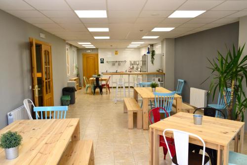 a cafeteria with wooden tables and chairs and a kitchen at Alda Estella Hostel in Estella