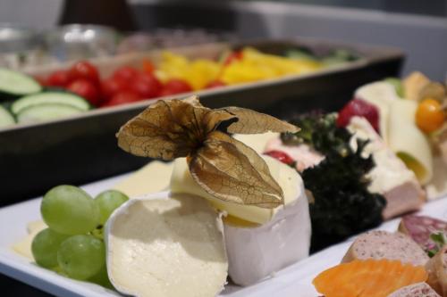 a plate of food with cheese grapes and other foods at Hotel Krämerbrücke Erfurt in Erfurt