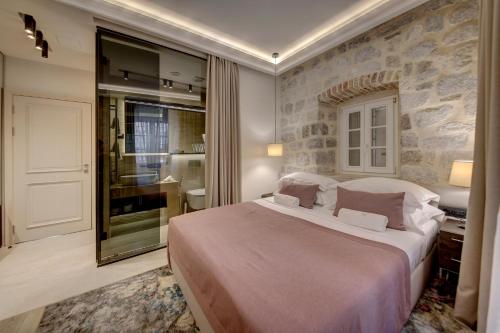 a bedroom with a large bed and a bathroom at Heritage Hotel Leon Coronato in Perast