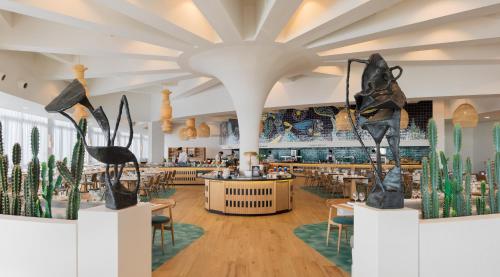 a restaurant with tables and chairs and sculptures on display at H10 Atlantic Sunset Horizons Collection in Adeje