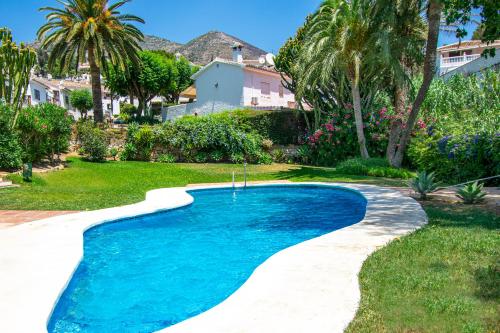 uma piscina num quintal com palmeiras e uma casa em Casa Christabel y Casa Annabel em Benalmádena