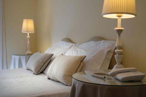 a bed with white pillows and a table with a lamp at Ambasciatori Palace in Montecatini Terme