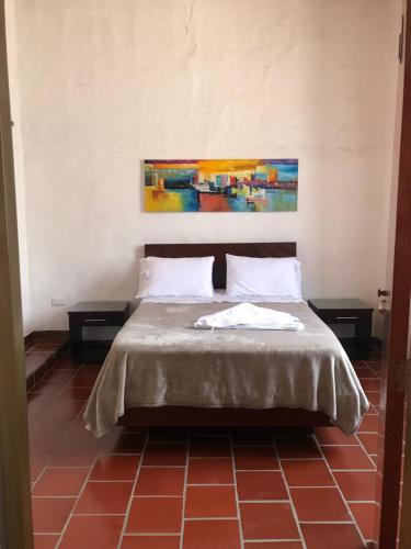 una camera da letto con un letto con due tavoli e un quadro di Hostal Rous San Gil a San Gil