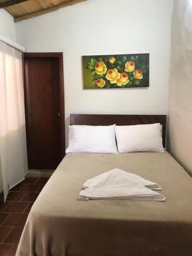 1 cama en un dormitorio con una pintura en la pared en Hostal Rous San Gil, en San Gil