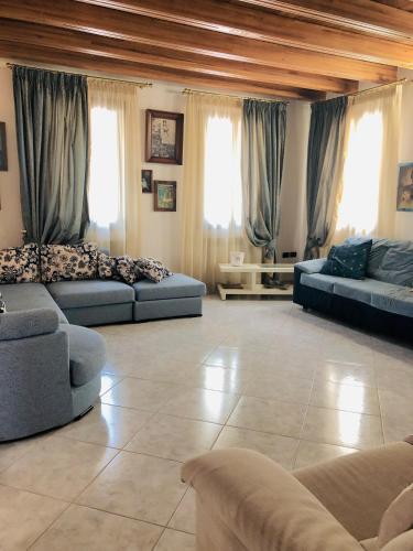 a large living room with blue couches and windows at Villamoreno in Merlara