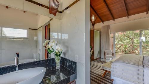 a bathroom with a sink and a tub and a bed at Ananda Pousada in Pirenópolis