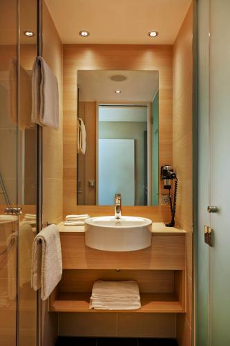 a bathroom with a sink and a mirror at H2 Hotel München Messe in Munich