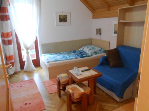 Habitación pequeña con cama y sofá azul en Aranyeső Vendégház Csorbai, en Budapest