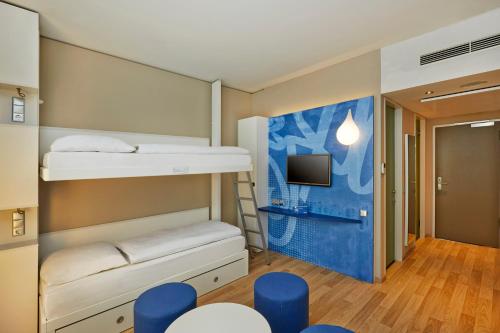 a room with two bunk beds and a tv at H2 Hotel München Messe in Munich