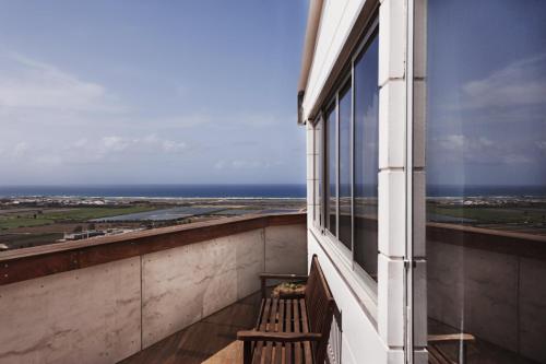 a bench on a balcony with a view of the ocean at Hotel Beit Maimon in Zikhron Ya‘aqov