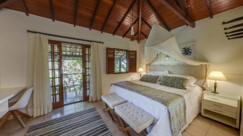 a bedroom with a bed and a desk and windows at Ananda Pousada in Pirenópolis