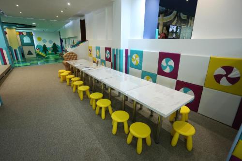 a classroom with a long table and yellow stools at Hotel Palisad in Zlatibor